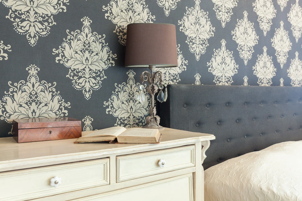 Chambre élégante avec tête de lit capitonnée grise, commode vintage blanc cassé aux tiroirs à poignées rondes