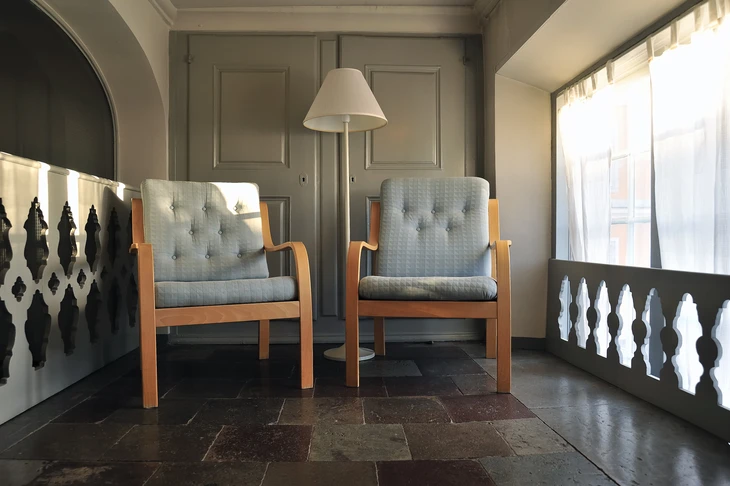 Salon d'attente professionnel avec deux fauteuils scandinaves en tissu gris chiné et structure bois clair, disposés face à face