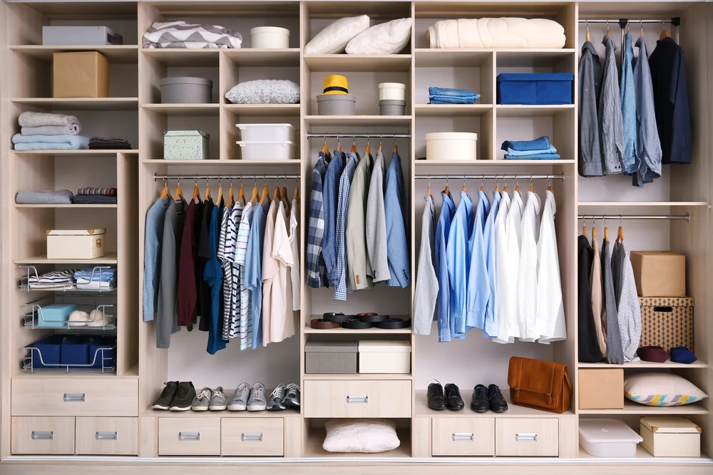 Dressing spacieux avec rangements modulaires en bois clair, vêtements suspendus sur tringles, chemises et costumes organisés par couleur