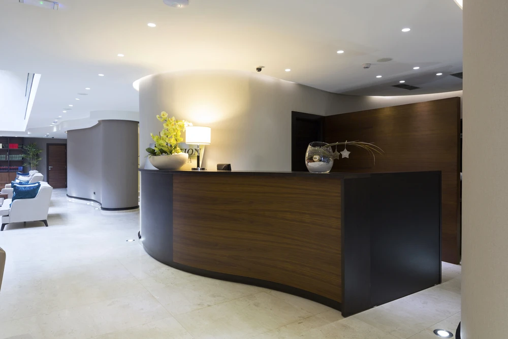 Espace d'accueil professionnel moderne avec banque d'accueil courbe en bois foncé et structure noire