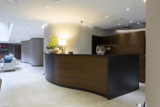 Espace d'accueil professionnel moderne avec banque d'accueil courbe en bois foncé et structure noire