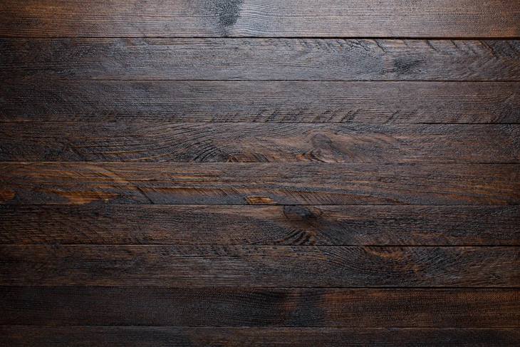 Surface de planches en bois massif disposées horizontalement, présentant des teintes brunes et grises naturelles avec des veines et nœuds apparents