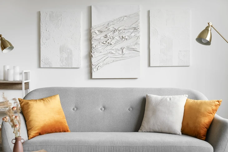 Salon moderne avec canapé gris à capitons, coussins orange et blanc