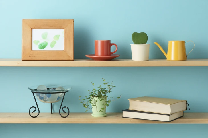 Scène d'intérieur minimaliste avec étagères murales en bois clair sur mur bleu pastel