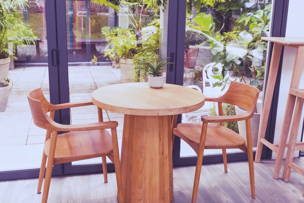 Intérieur moderne avec mobilier en bois naturel près de baies vitrées donnant sur terrasse végétalisée
