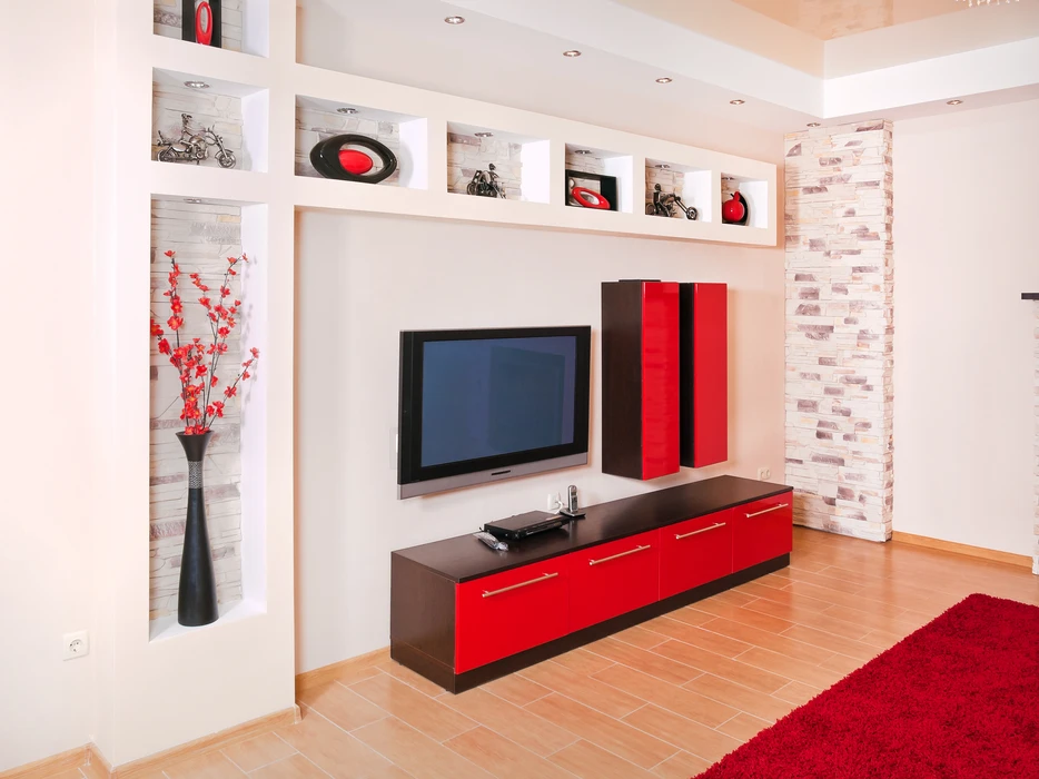 Salon moderne avec meuble TV mural rouge et noir, téléviseur à écran plat intégré dans niche blanche