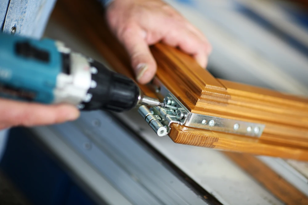 Atelier de menuiserie intérieur avec artisan installant une ferrure de meuble en bois