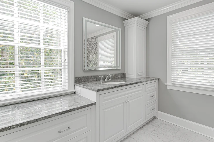 Salle de bain moderne avec mobilier blanc laqué, plan de travail en granit gris veiné, vasque encastrée et robinetterie chromée