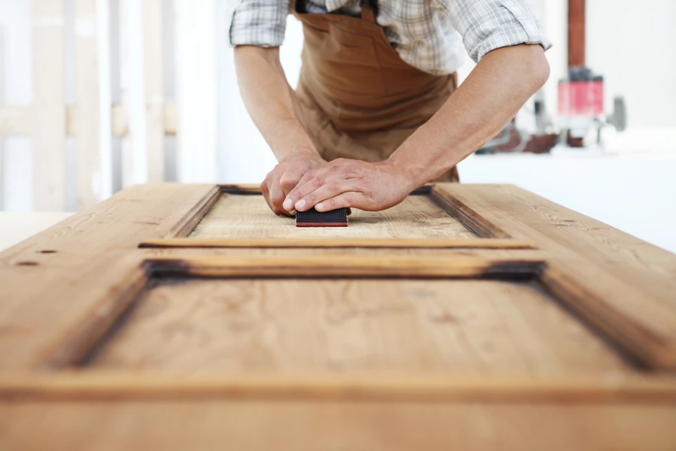 Atelier de menuiserie intérieur avec artisan en tablier travaillant sur cadres en bois