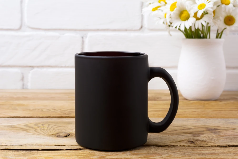 Scène d'intérieur cuisine moderne avec mug noir mat posé sur plan de travail en bois naturel