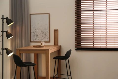 Espace de travail moderne avec table haute en bois naturel, deux chaises bar noires, lampadaire articulé triple