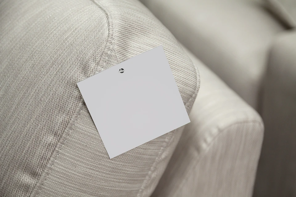 Intérieur professionnel avec note adhésive blanche carrée fixée par punaise sur textile beige structuré, surface rembourrée visible en arrière-plan flou