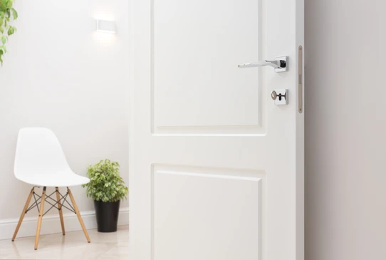 Intérieur moderne avec porte blanche à panneaux moulurés, poignée chromée et serrure