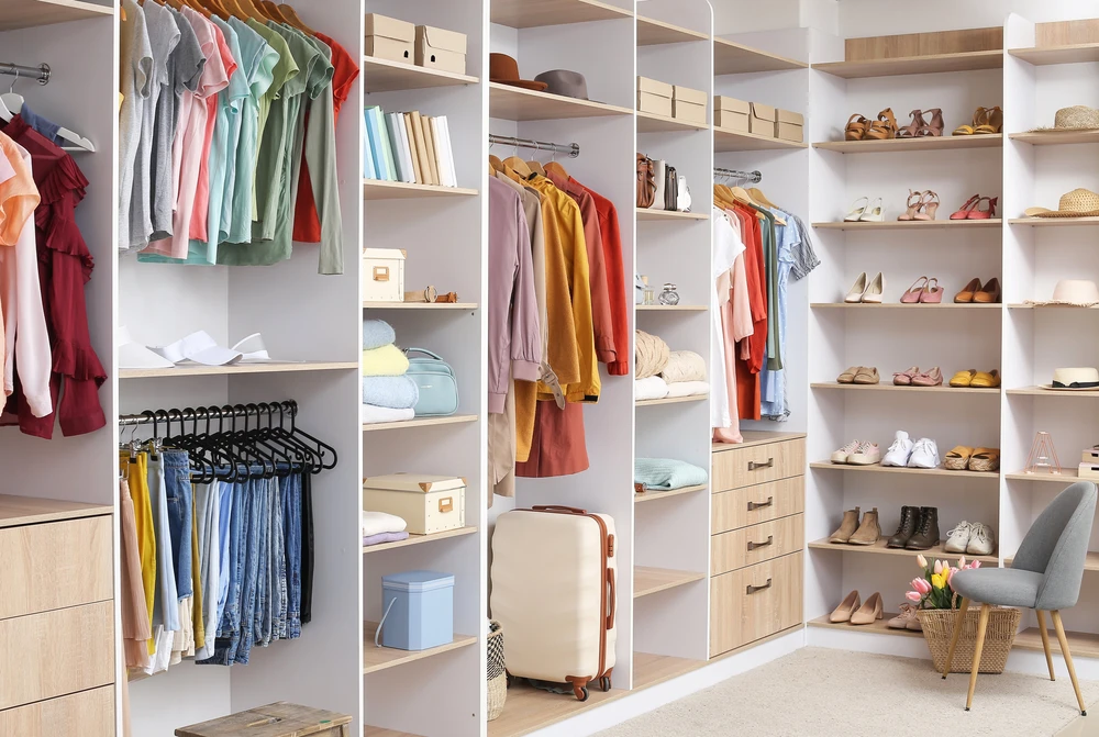 Grande penderie avec différents vêtements et accessoires dans le dressing