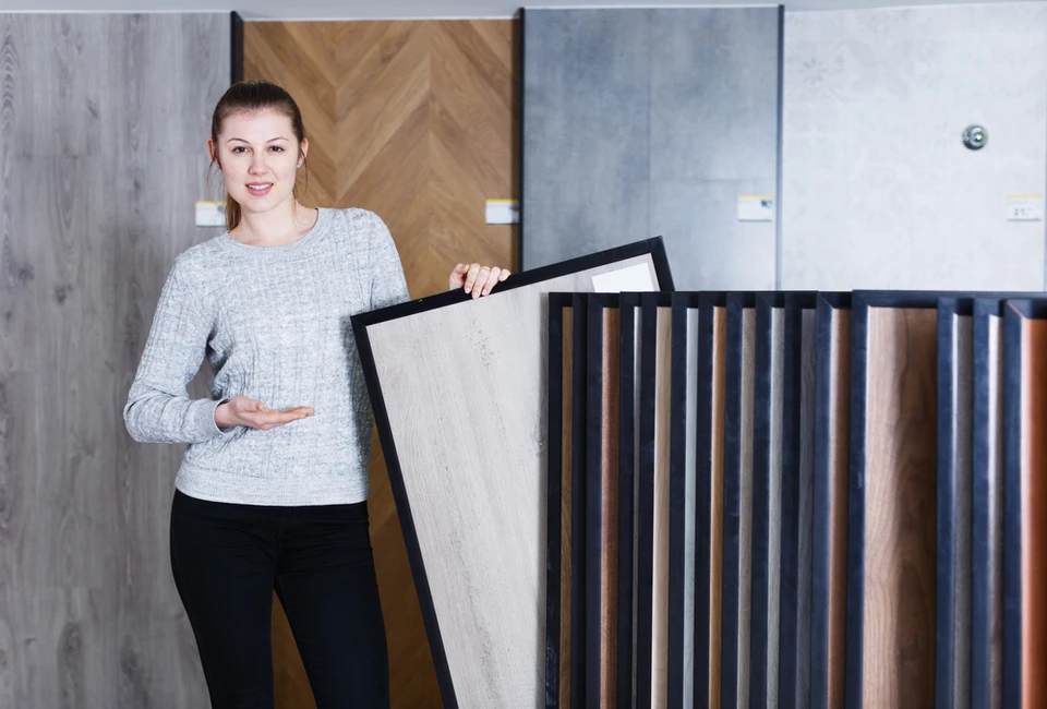 Femme souriante présentant échantillon de parquet dans showroom d'aménagement intérieur
