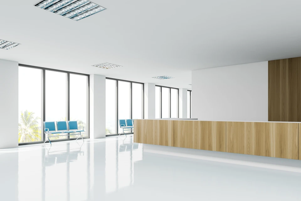 Espace d'accueil moderne avec banque d'accueil courbe en bois clair, chaises bleues design contre baies vitrées panoramiques