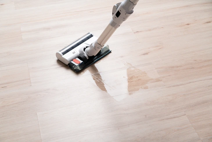 Nettoyage de parquet en bois clair avec aspirateur-laveur électrique à main