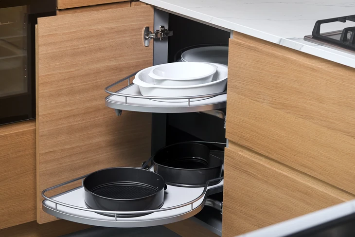Cuisine moderne avec meuble d'angle ouvert révélant un système de rangement rotatif à plateaux coulissants