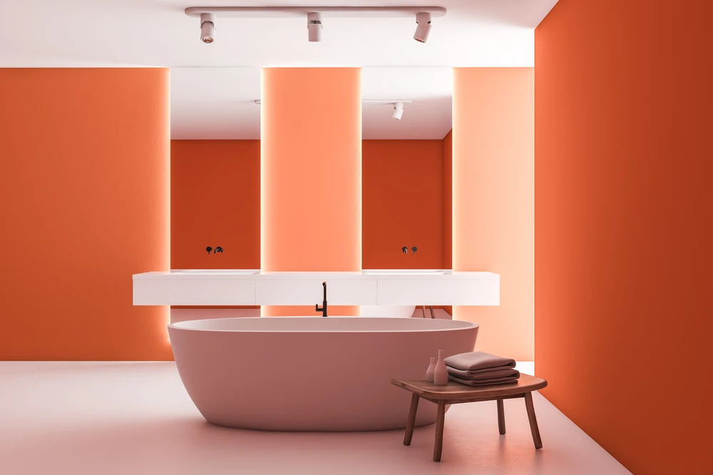 Salle de bain moderne aux murs orange vif avec baignoire îlot rose poudré et vasque suspendue blanche