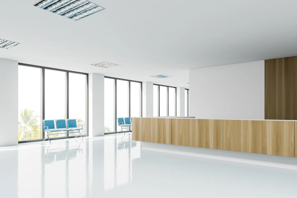 Espace d'accueil moderne avec banque d'accueil courbe en bois clair, chaises bleues design contre baies vitrées panoramiques