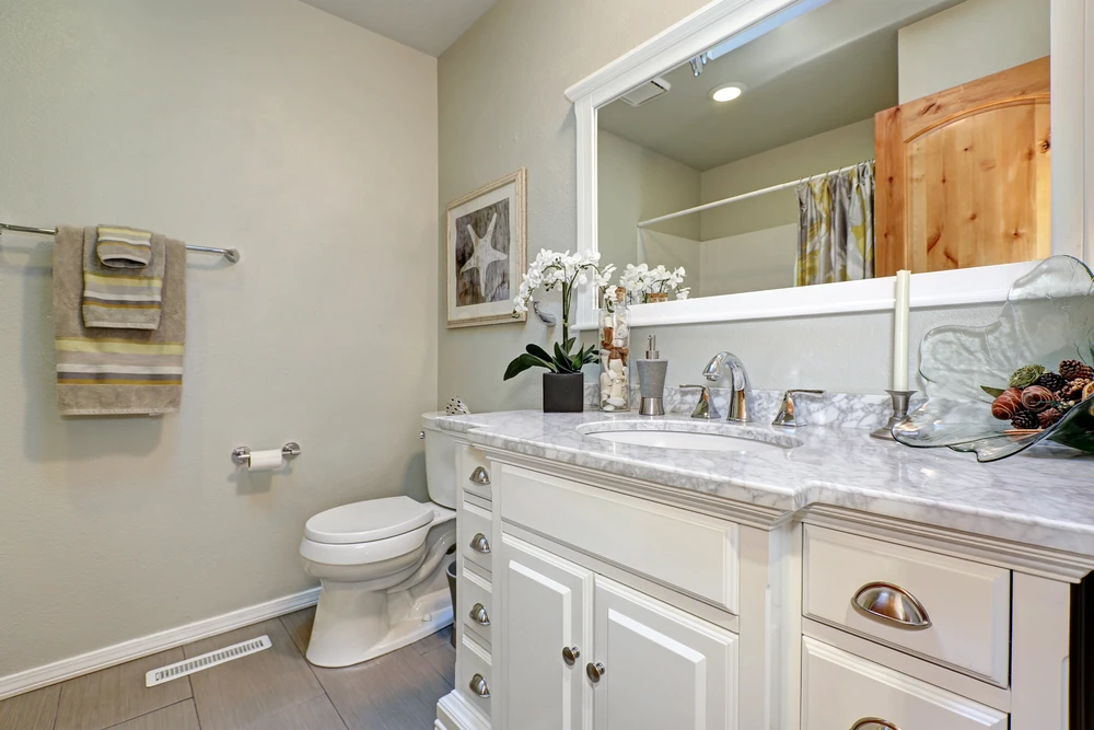 Salle de bain moderne avec meuble-lavabo blanc à tiroirs, plan de travail en marbre veiné, robinetterie chromée trois trous
