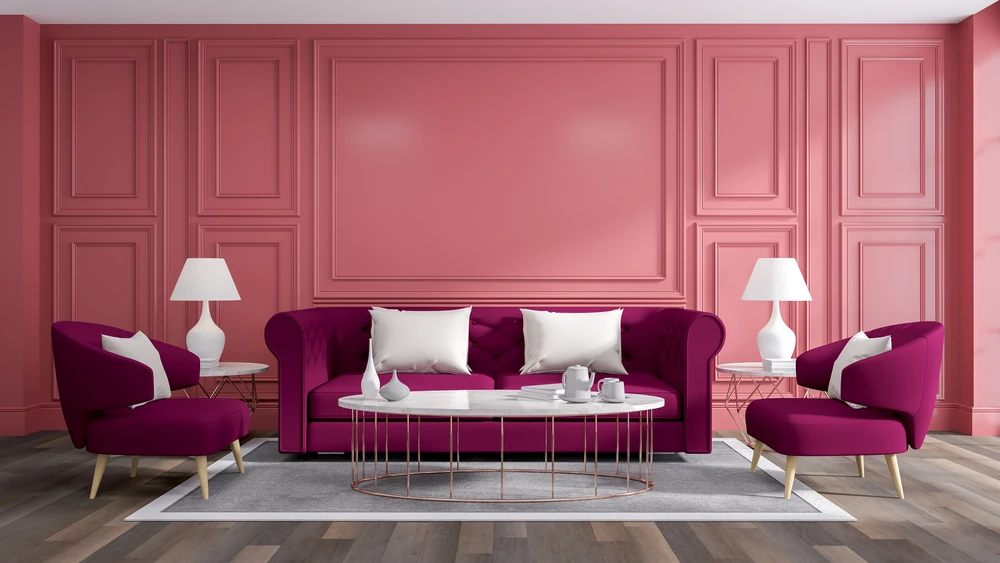 Salon luxueux avec canapé et fauteuils en velours bordeaux, coussins blancs, table basse ronde en métal doré