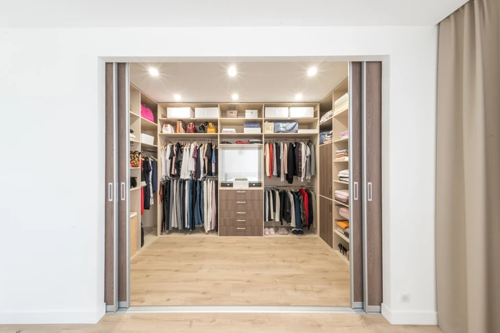 Dressing spacieux moderne avec portes coulissantes ouvertes révélant un aménagement intérieur organisé